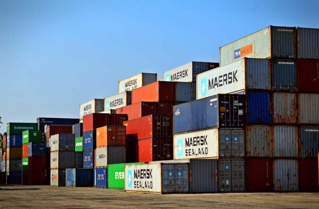 Home Colorful stacked shipping containers at a port exemplify global logistics.